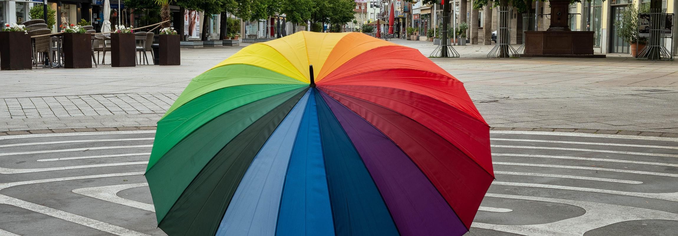Bunter Regenschirm steht aufgespannt auf dem Marktplatz