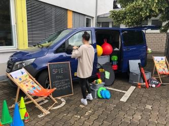 Frau baut Spielzeug vor Spielmobil auf