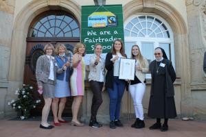Gruppenbild mit Fairtrade Urkunde vor der Sancta Maria Fachschule in