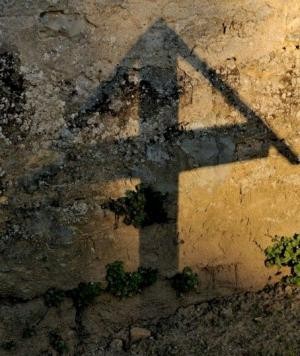 Schatten eines Kreuzes auf Hauswand