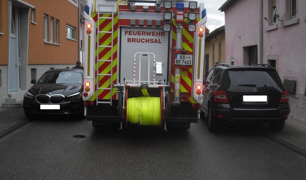 Feuerwehrfahrzeug versucht zwischen zwei parkenden Autos durchzukommen.               . 