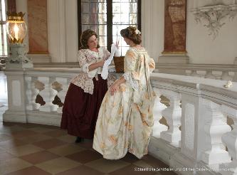 Kostümführung in Schloss Bruchsal Zwei kostümierte Frauen in historischen Gewändern unterhalten sich im Schloss Bruchsal.