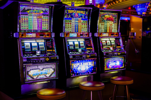 Drei beleuchtete Glückspielautomaten mit drei Hockern