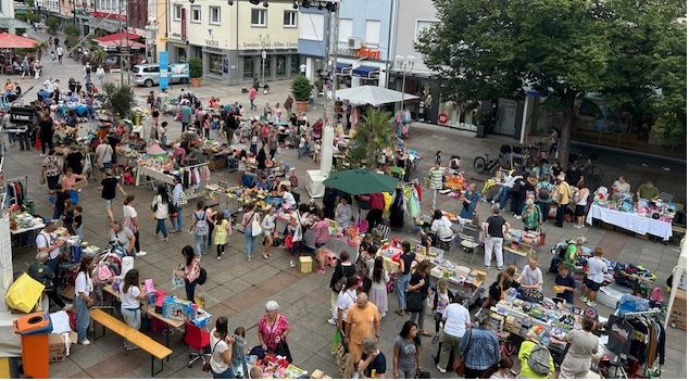 Belebter Rathausvorplatz mit vielen Menschen und Verkaufsständen.