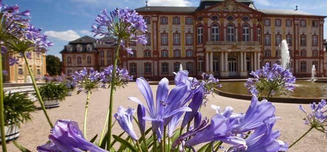 Foto von Schloss Bruchsal mit lila Blüten im Vordergrund, Foto: SSG/Achim Mende