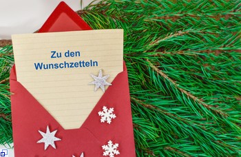Roter Briefumschlag mit herausschauendem Zettel "Zu den Wunschzetteln", Tannenzweige im Hintergrund