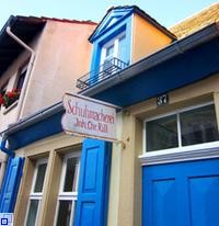 Häuschen mit blauem Fensterläden und Schild "Schumacherei Inh. Chr. Rill"