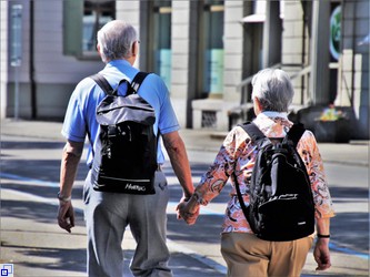 Älteres Paar lauft Händchenhalten durch die Stadt 